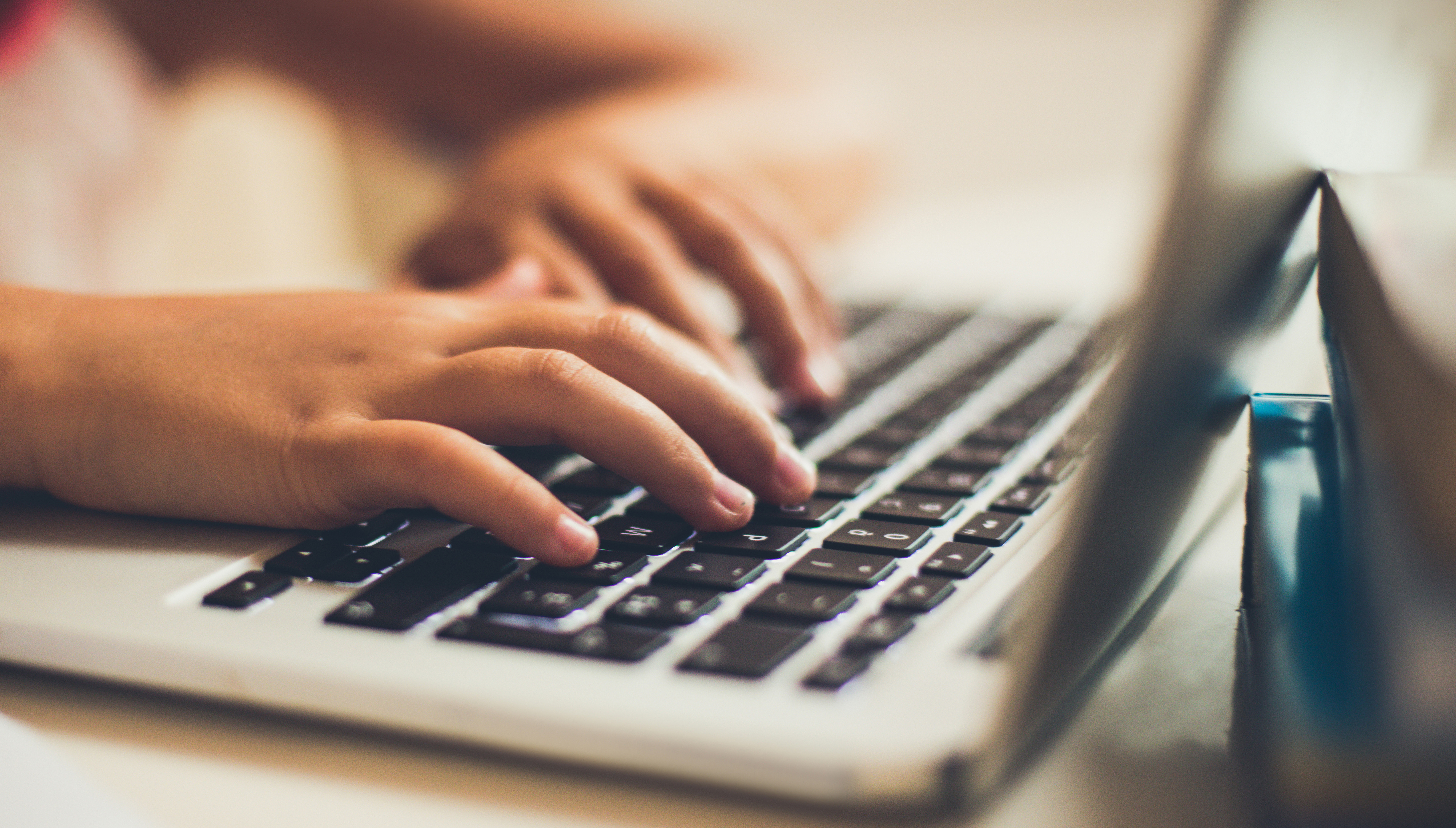 Close-up van kinderhanden aan een klavier van een laptop