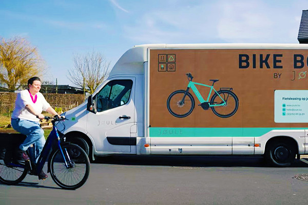 vrouw fietst op straat voorbij vrachtwagen van Joule fietslease